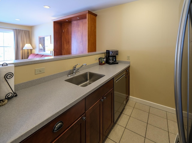 kitchen featuring a sink, stainless steel dishwasher, light countertops, light tile patterned floors, and baseboards