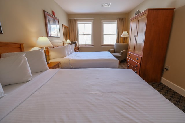 bedroom featuring visible vents, baseboards, and dark colored carpet