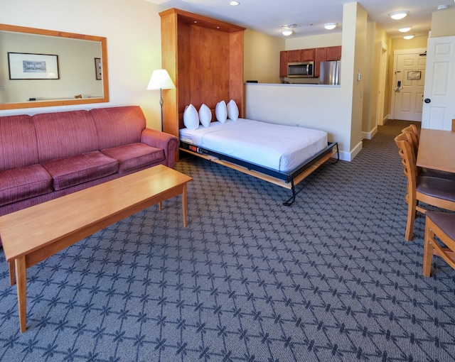 bedroom with dark carpet, freestanding refrigerator, and baseboards