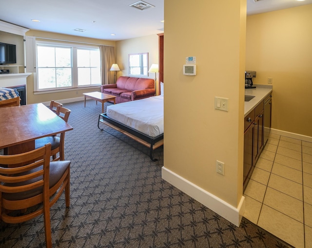 bedroom with light tile patterned floors, visible vents, a fireplace, and baseboards