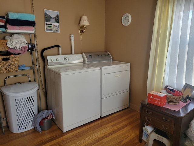 laundry area featuring washing machine and clothes dryer, laundry area, and wood finished floors