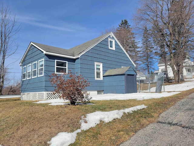 view of home's exterior featuring a yard, fence, and roof with shingles