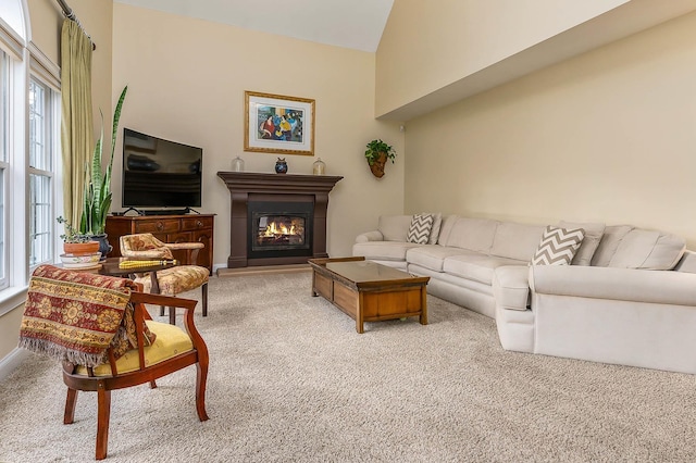 living room with a glass covered fireplace, light colored carpet, and lofted ceiling