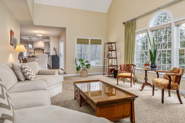 living room featuring light carpet, plenty of natural light, high vaulted ceiling, and baseboards