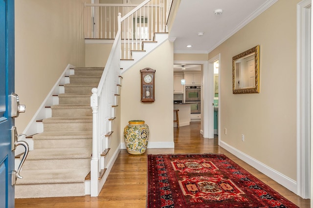 entrance foyer featuring stairway, wood finished floors, baseboards, and ornamental molding