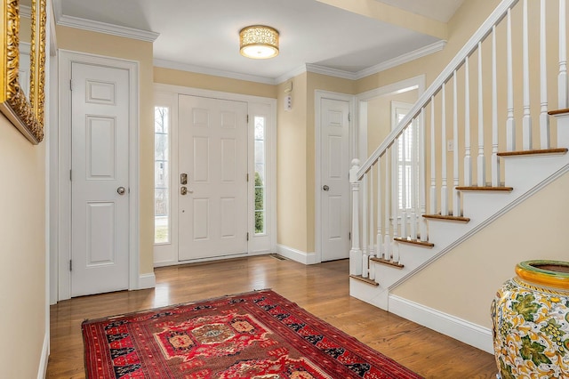 entryway with stairway, wood finished floors, baseboards, and ornamental molding