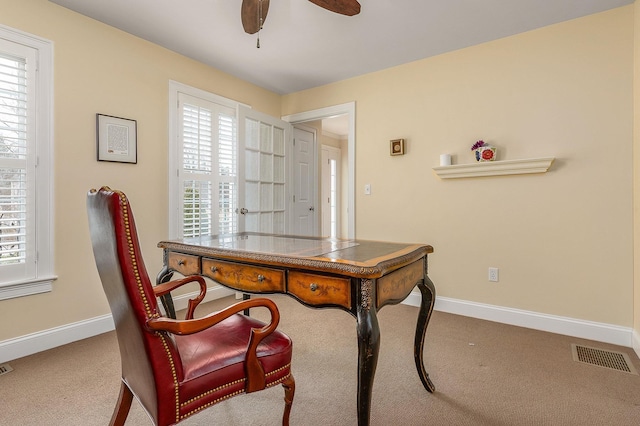 office space with carpet, a ceiling fan, visible vents, and baseboards