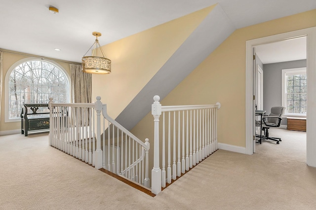 corridor with an upstairs landing, baseboards, and carpet floors