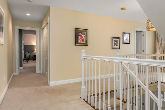 hallway featuring recessed lighting, baseboards, carpet, and an upstairs landing