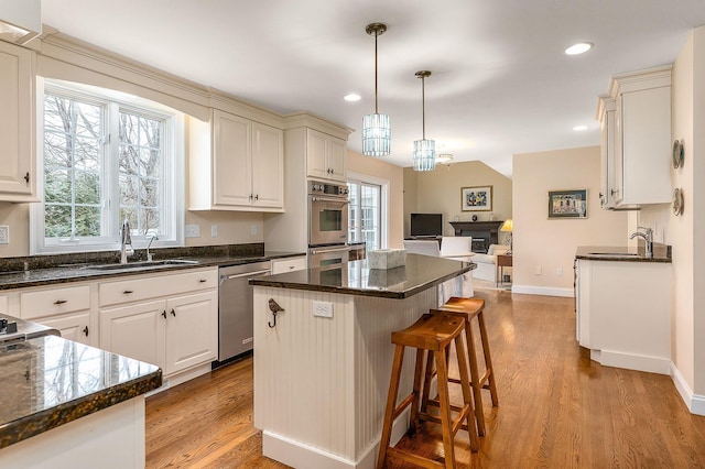 kitchen featuring a center island, open floor plan, a kitchen bar, light wood-type flooring, and appliances with stainless steel finishes