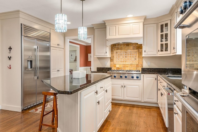 kitchen featuring stainless steel appliances, glass insert cabinets, a kitchen island, and wood finished floors