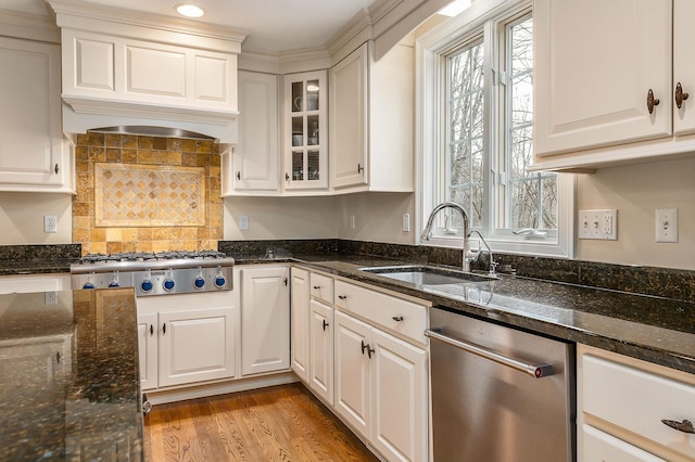 kitchen with dark stone countertops, appliances with stainless steel finishes, light wood-style floors, white cabinets, and a sink