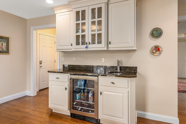 bar featuring a sink, wood finished floors, wine cooler, wet bar, and baseboards