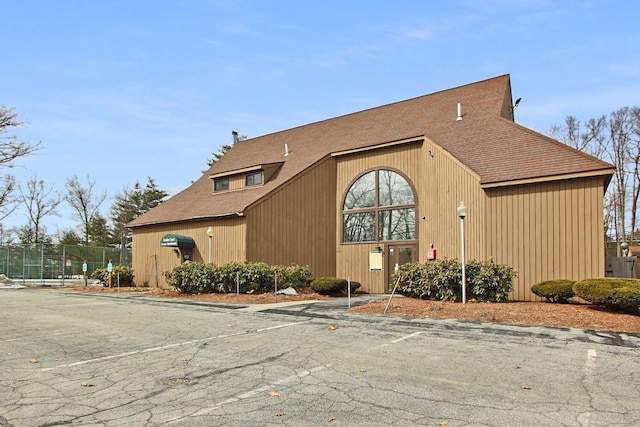 view of home's exterior featuring fence and a shingled roof