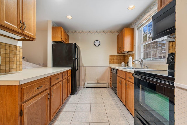 kitchen featuring light tile patterned floors, a sink, black appliances, brown cabinets, and baseboard heating