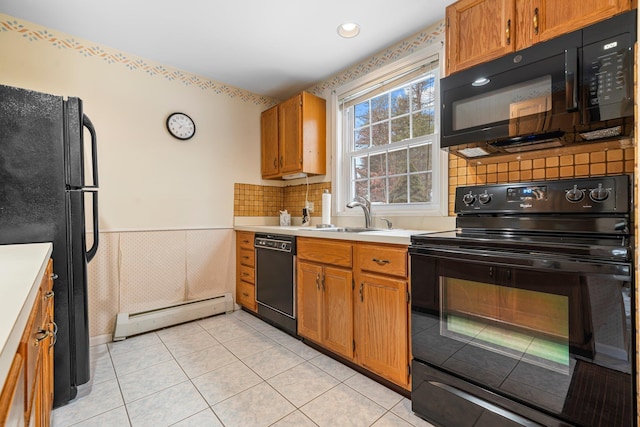 kitchen with black appliances, a sink, a baseboard heating unit, wainscoting, and light countertops