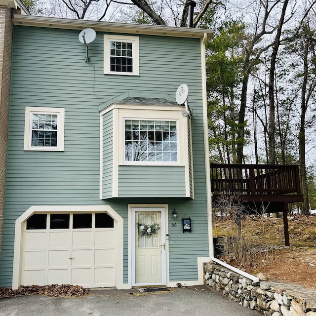 view of front facade featuring a garage, a deck, and aphalt driveway