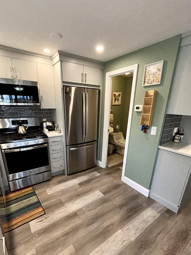 kitchen featuring backsplash, stainless steel appliances, light countertops, and light wood-style floors