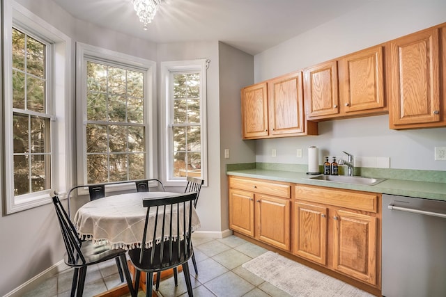 kitchen with a sink, stainless steel dishwasher, light tile patterned flooring, light countertops, and baseboards