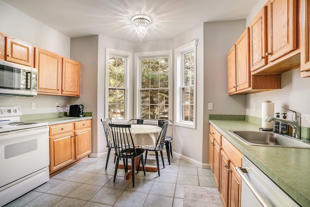 kitchen with white electric range oven, light tile patterned floors, a sink, dishwasher, and stainless steel microwave