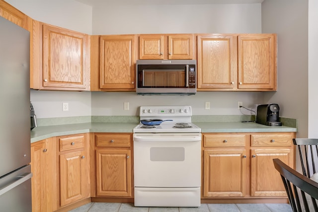 kitchen featuring appliances with stainless steel finishes, light tile patterned flooring, and light countertops