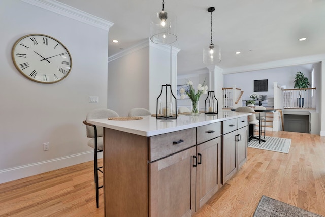 kitchen featuring crown molding, baseboards, pendant lighting, a breakfast bar, and light wood-style floors