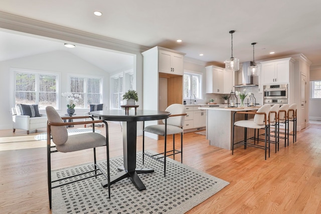 kitchen with light countertops, wall chimney exhaust hood, a center island, and white cabinetry