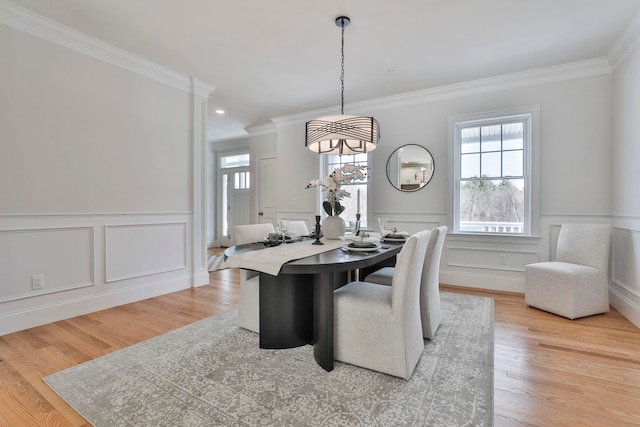 dining room with light wood-type flooring, wainscoting, and crown molding