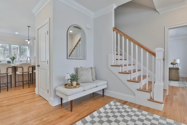 foyer featuring stairway, light wood-style floors, and ornamental molding