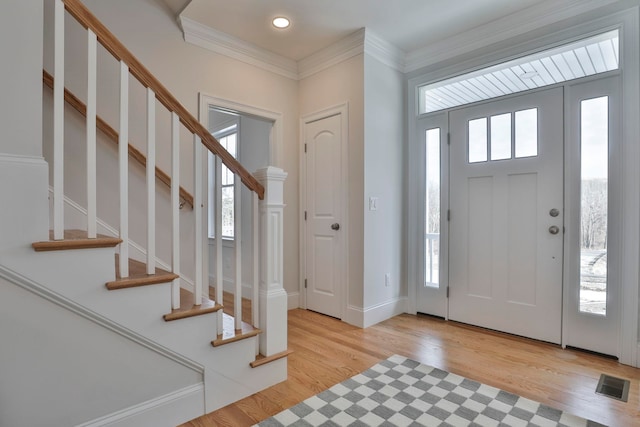 entrance foyer with a wealth of natural light, visible vents, crown molding, and light wood finished floors