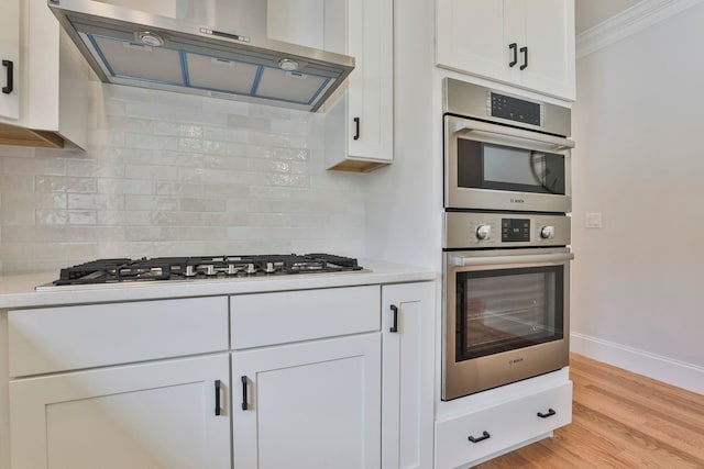 kitchen featuring light wood-style floors, stainless steel appliances, extractor fan, and light countertops