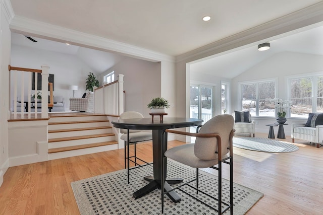 dining space featuring light wood finished floors, stairway, and lofted ceiling