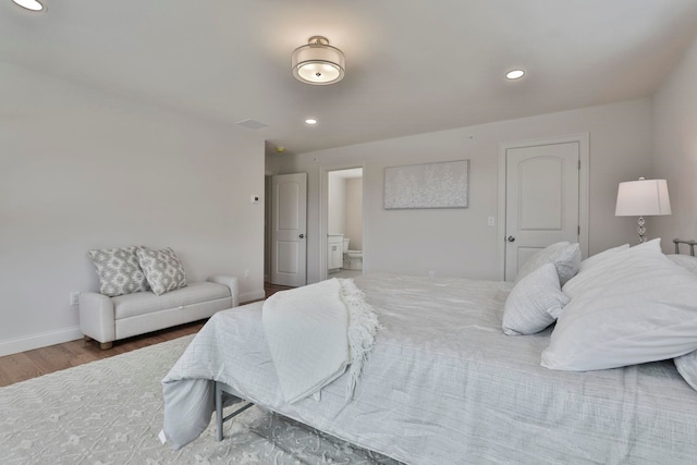 bedroom with recessed lighting, connected bathroom, baseboards, and wood finished floors