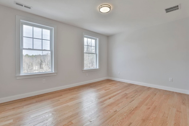 unfurnished room featuring baseboards, visible vents, and light wood-type flooring