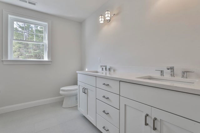 bathroom with double vanity, toilet, visible vents, and a sink