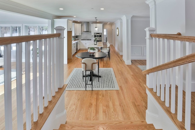 dining room with decorative columns, ornamental molding, and light wood finished floors