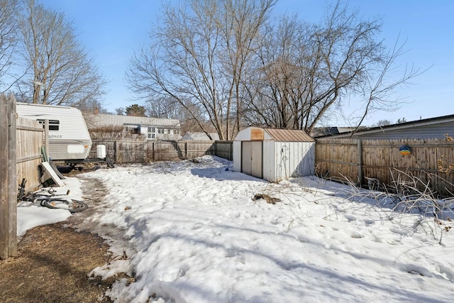 yard layered in snow with an outbuilding, a storage unit, and a fenced backyard