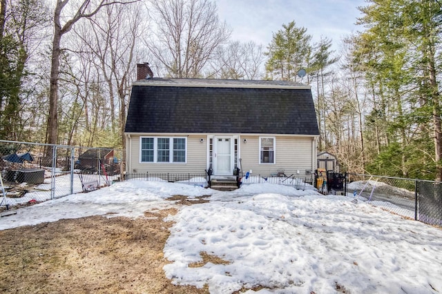 view of front facade featuring fence, roof with shingles, a gambrel roof, a chimney, and an outdoor structure