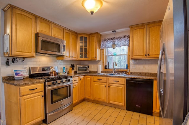 kitchen featuring a sink, backsplash, appliances with stainless steel finishes, a toaster, and glass insert cabinets