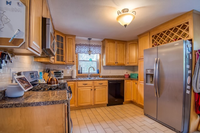 kitchen with dark countertops, backsplash, stainless steel appliances, and a sink