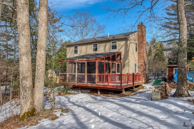 snow covered rear of property featuring a deck and a chimney