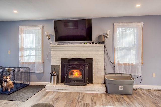 living area featuring recessed lighting, baseboards, wood finished floors, and a wood stove