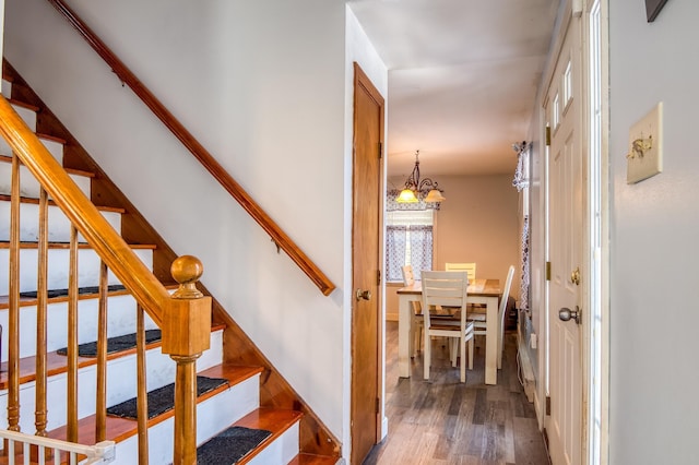 stairs featuring a chandelier and wood finished floors