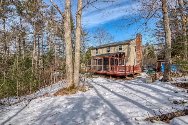 snow covered property featuring a wooden deck and a chimney