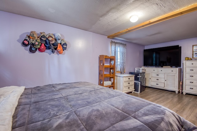 bedroom featuring beam ceiling and wood finished floors