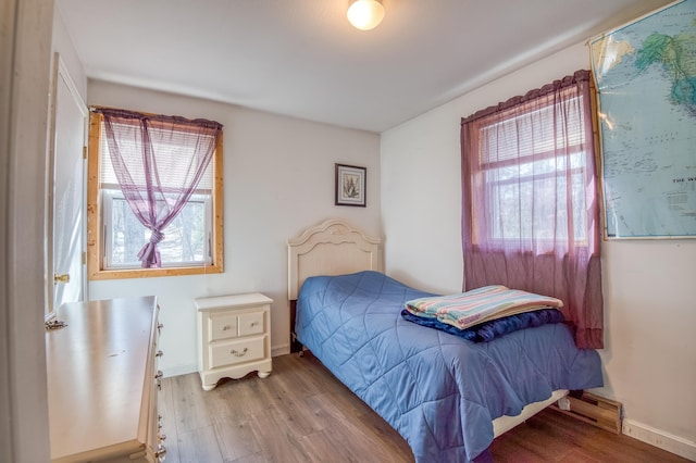 bedroom with baseboards, a baseboard heating unit, and light wood-style floors