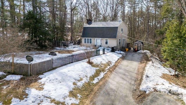 exterior space featuring fence, driveway, an outdoor fire pit, a gambrel roof, and a chimney