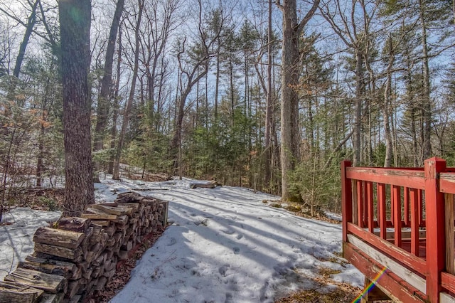 yard layered in snow featuring a wooded view