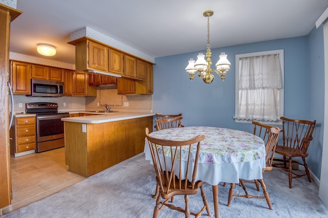 kitchen with tasteful backsplash, stainless steel appliances, light countertops, and an inviting chandelier