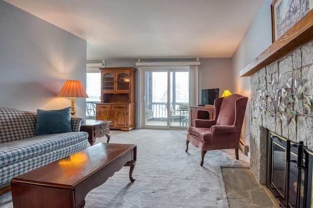 living room featuring a stone fireplace, carpet floors, and a baseboard heating unit